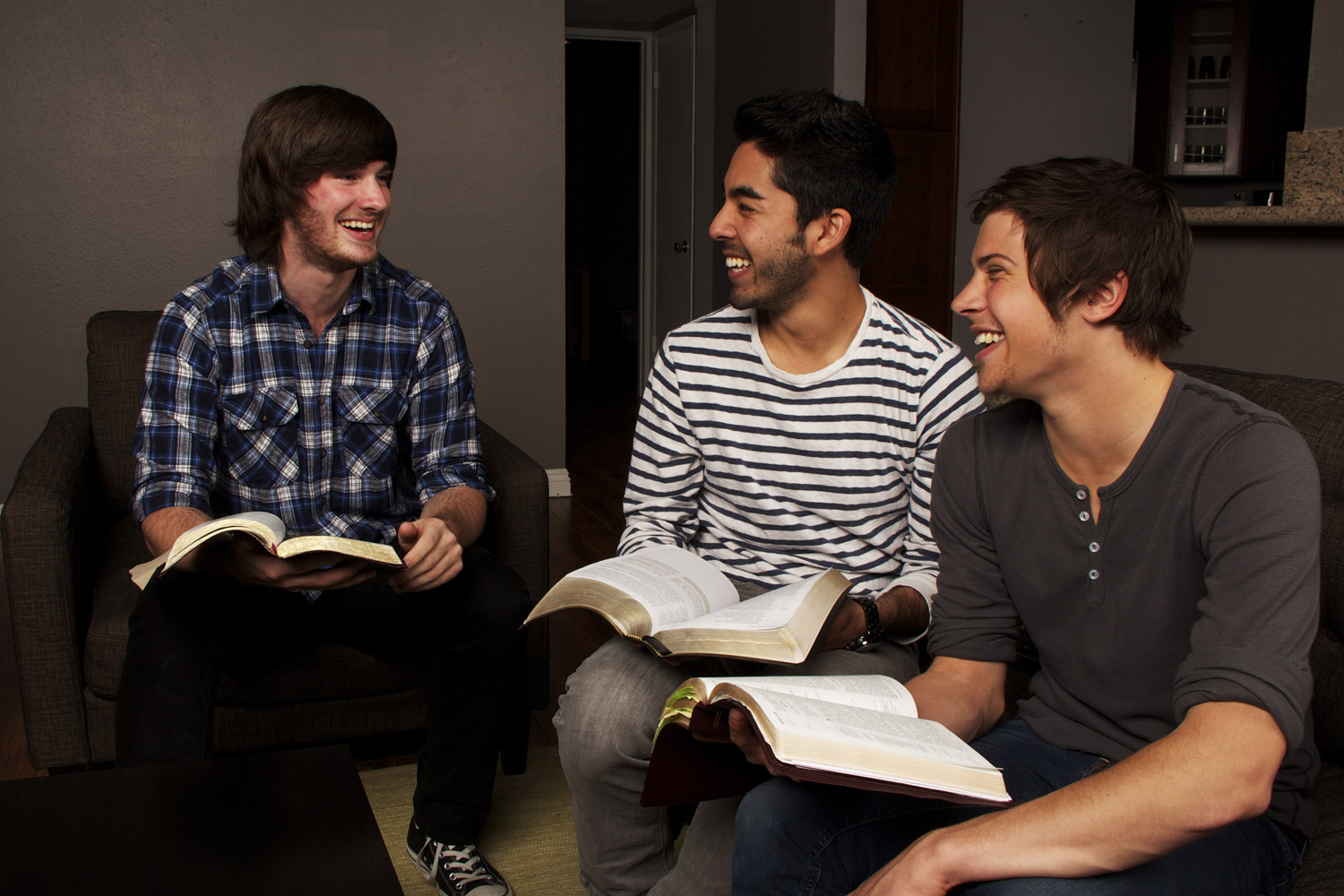 three men sitting and talking with open bibles