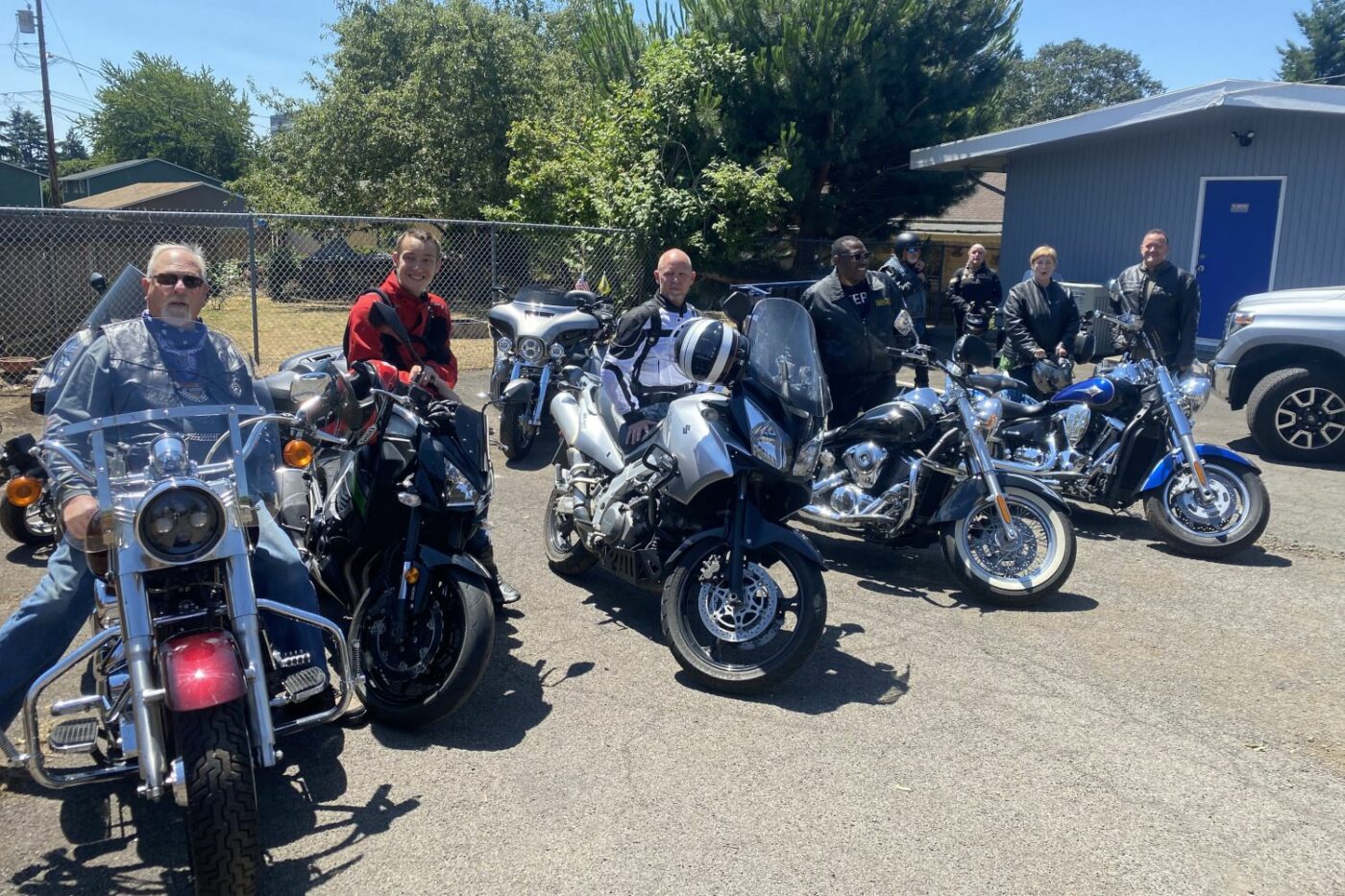 motorcycle riders posing with their bikes in the church parking lot